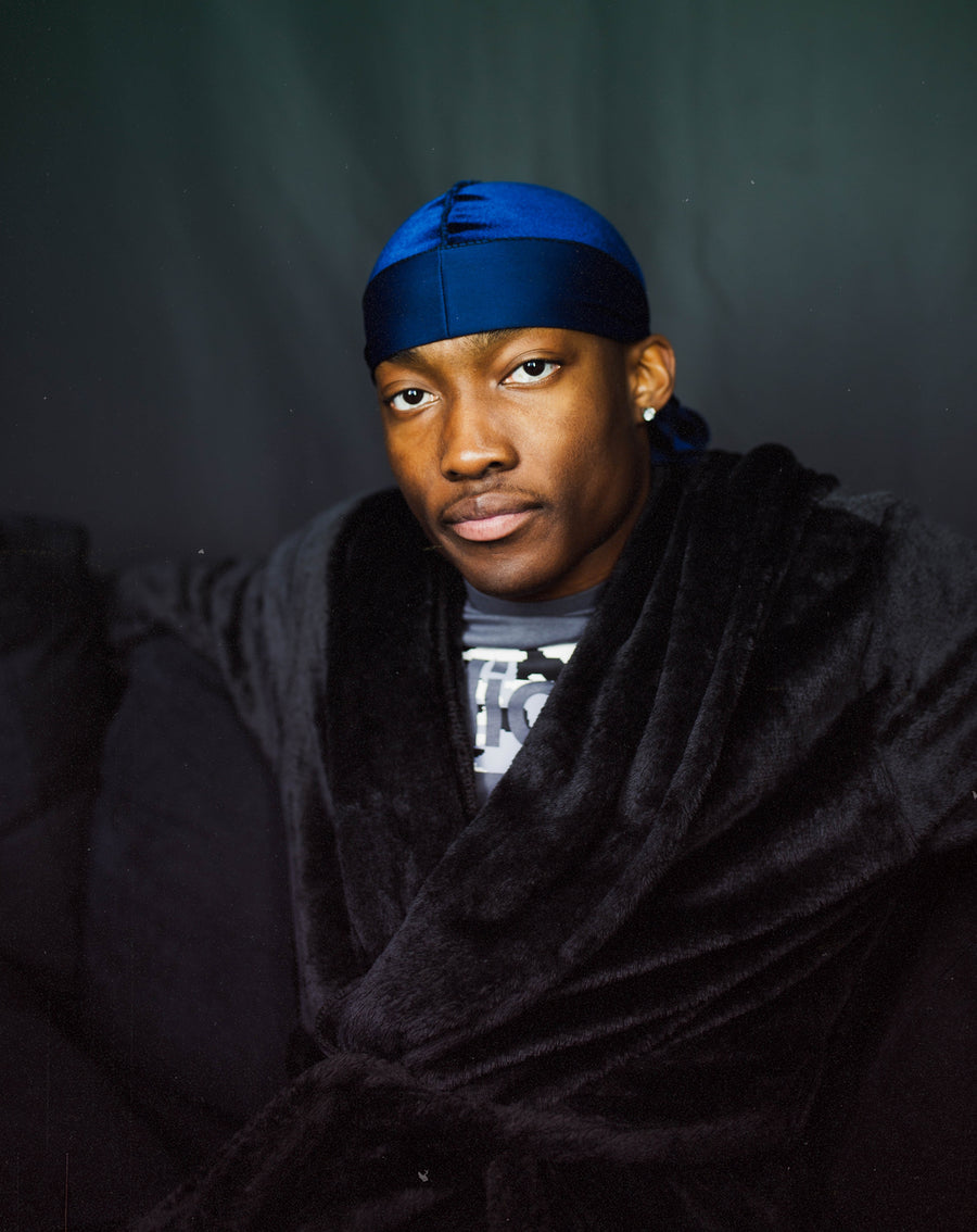 Guy sitting in dressing gown, wearing a durag